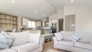 Een moderne woonkamer met twee banken, een salontafel en een keuken op de achtergrond.