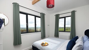 Et soveværelse med en seng, grønne gardiner, et vindue med udsigt og en rød lampe.
