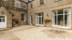 A courtyard with stone buildings, a fireplace, and outdoor seating. - The Coach House (Belford)