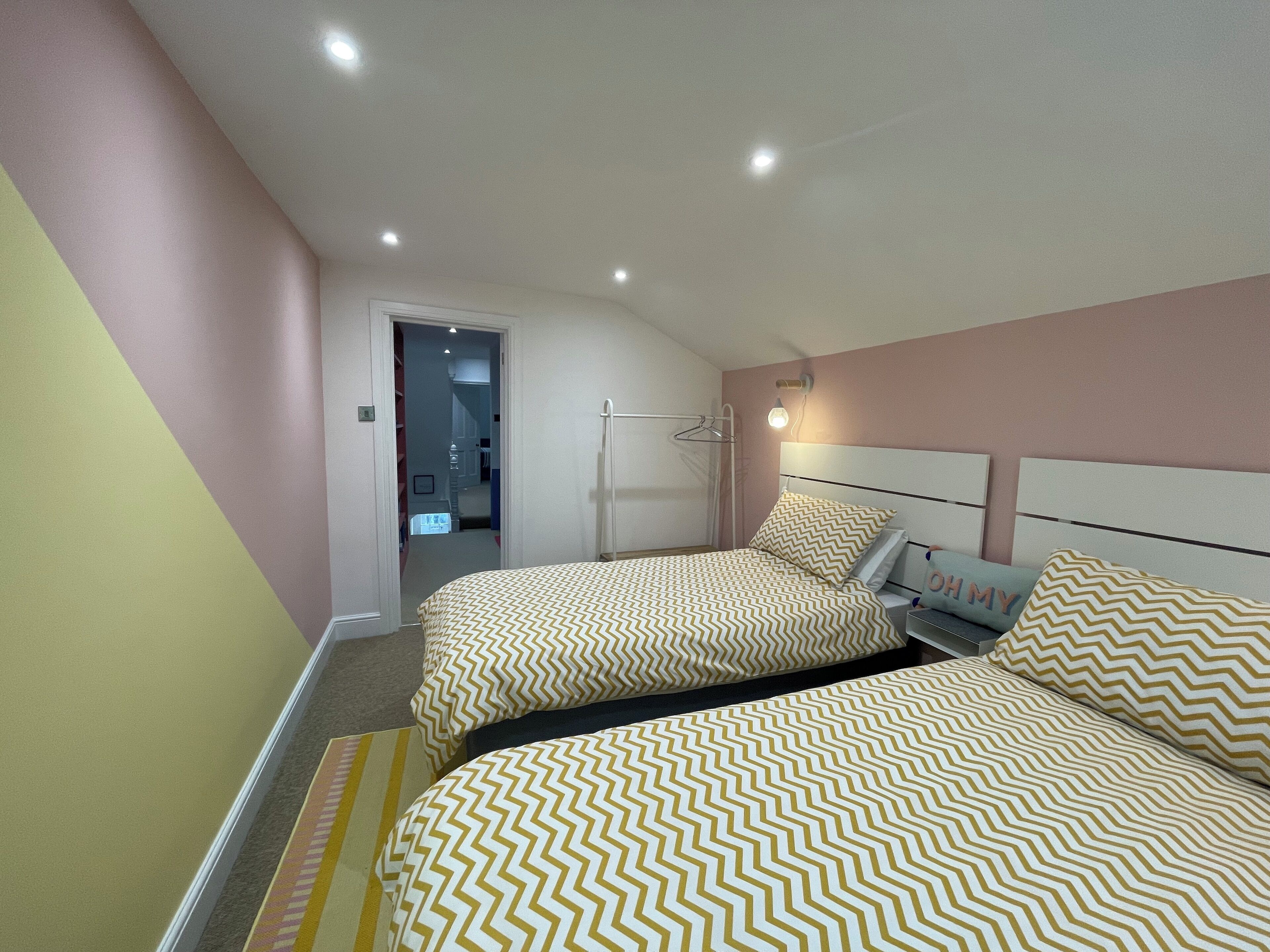 A bedroom with two beds, a wardrobe, and a door leading to a bathroom.