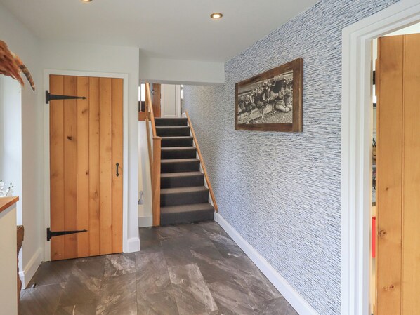 A hallway with a wooden door, a staircase, and a textured wall. - Haystacks (Windermere)