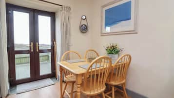 A dining area with a wooden table and chairs, a clock on the wall, and a framed picture.