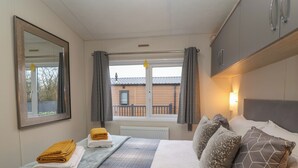 Hotellihuone, jossa on sänky, ikkuna verhoilla, patteri ja näkymä ulkona olevaan rakennukseen.