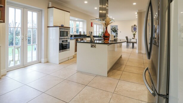 A modern kitchen with a central island, built-in appliances, and large windows. - Hardy's Way 34 (Canvey Island)