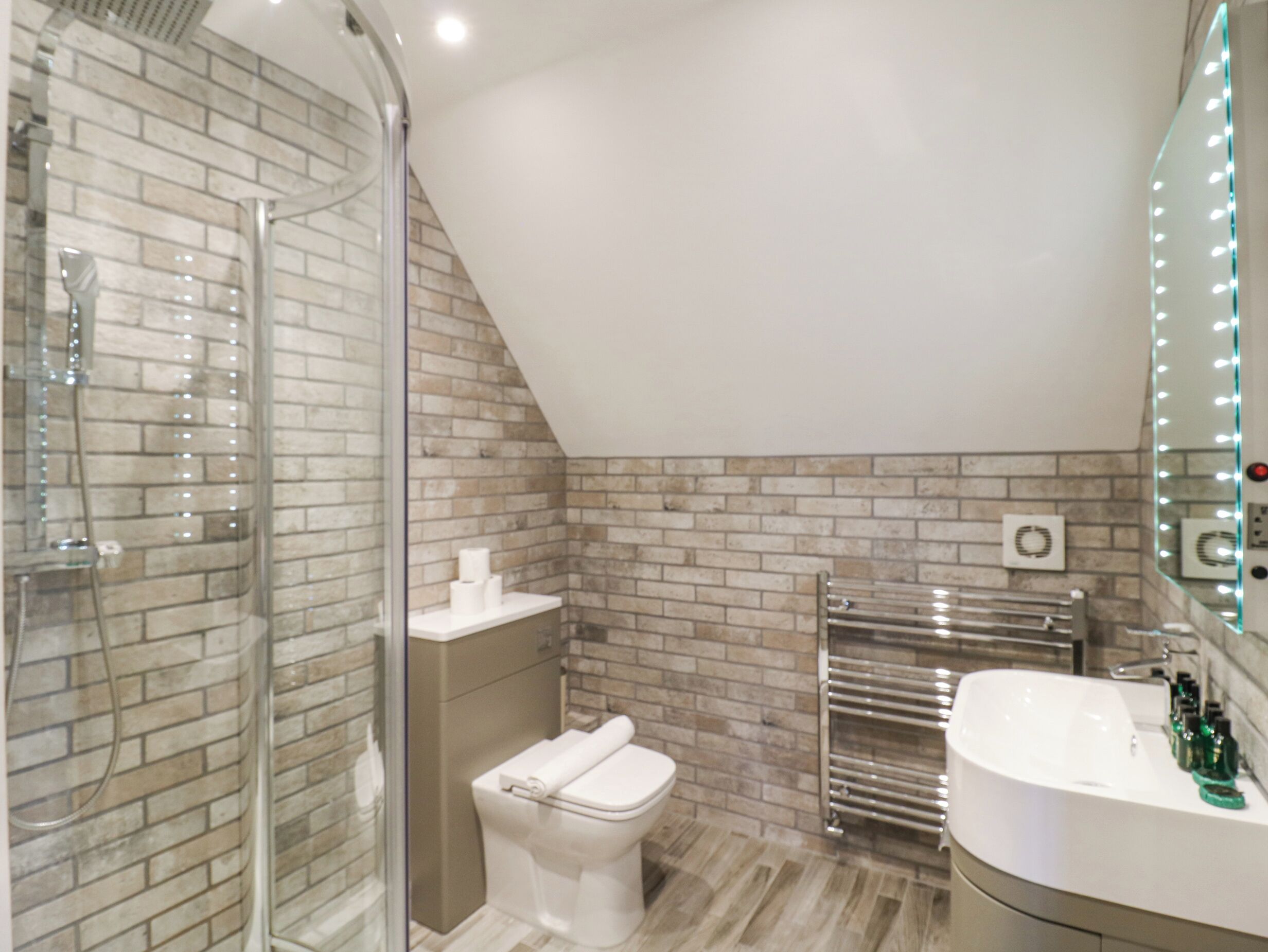Une salle de bain moderne avec une douche à parois de verre, des toilettes blanches, un meuble-lavabo avec un miroir et un porte-serviettes.