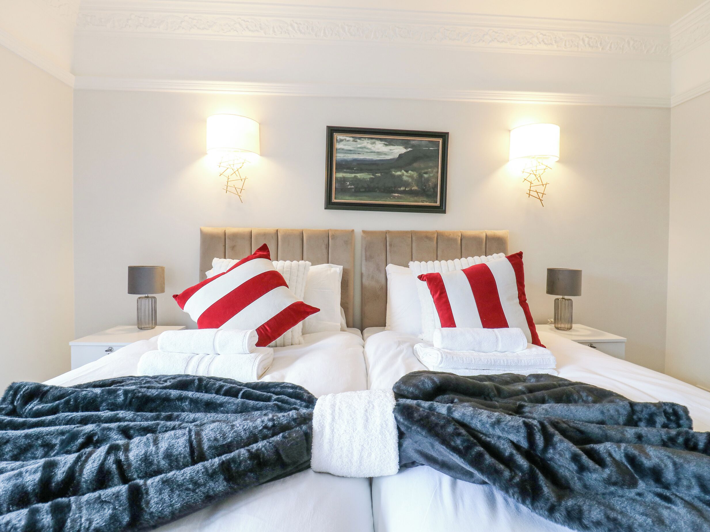 A hotel room with a large bed, two bedside tables with lamps, a painting on the wall, and a decorative ceiling medallion.