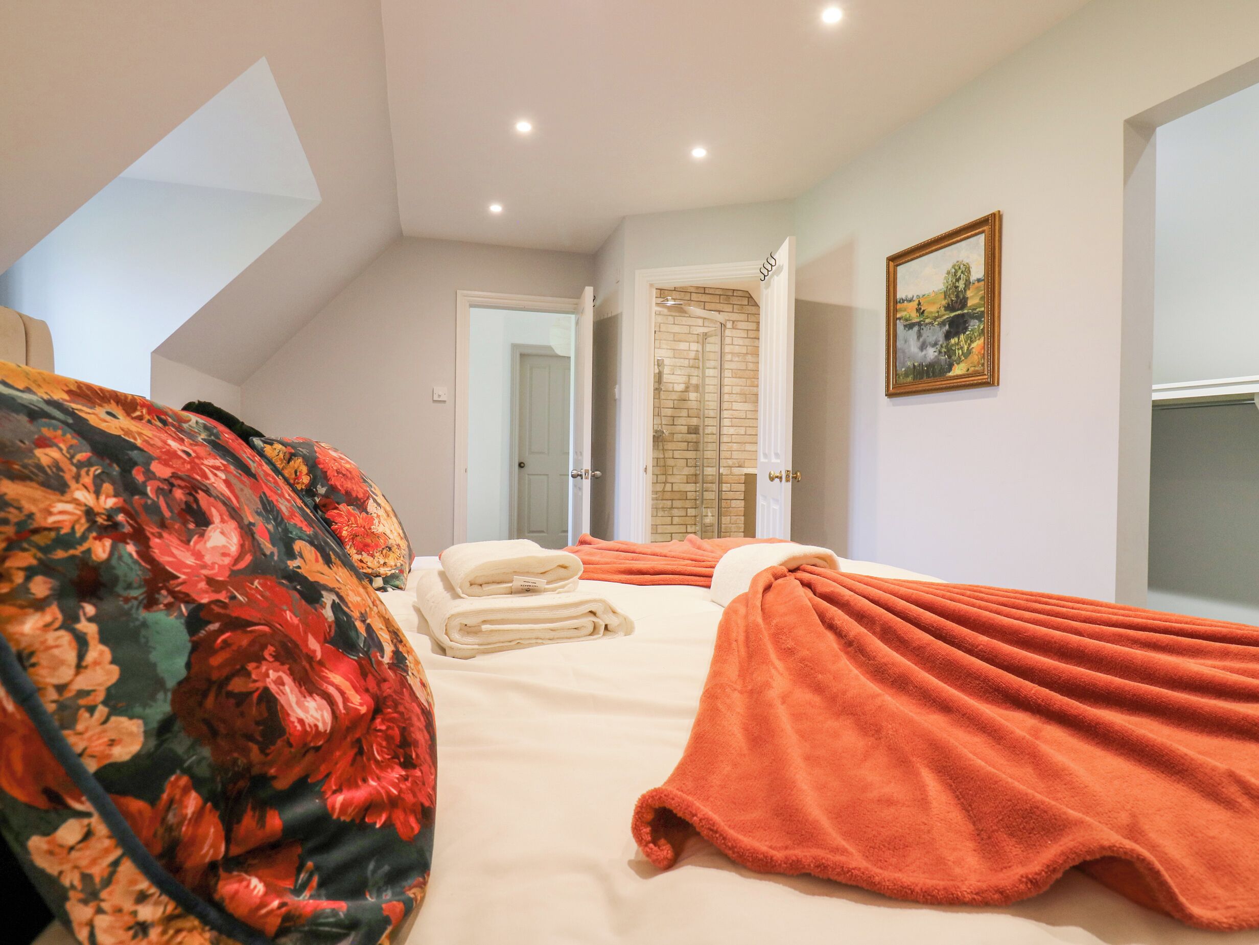 Una camera da letto con un letto, uno spazio doccia e un quadro appeso al muro.