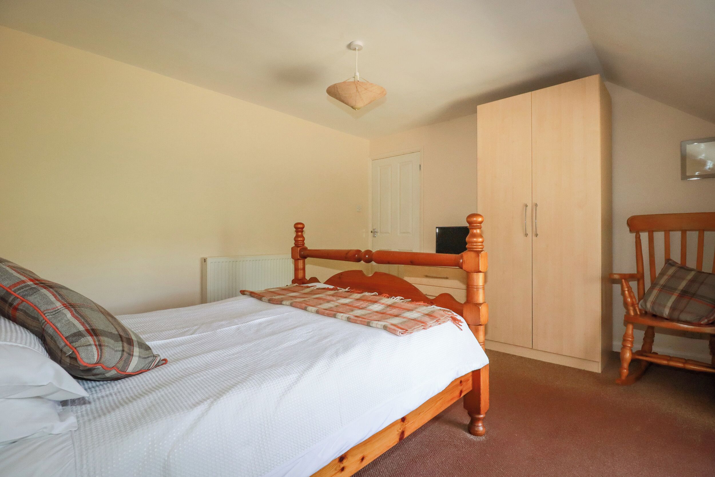 Una camera da letto con un letto di legno, un'armadio e una sedia.