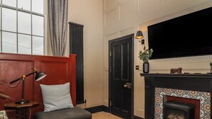 A living room with a fireplace, a television, a sofa, and a lamp. - The Court (Carnforth)