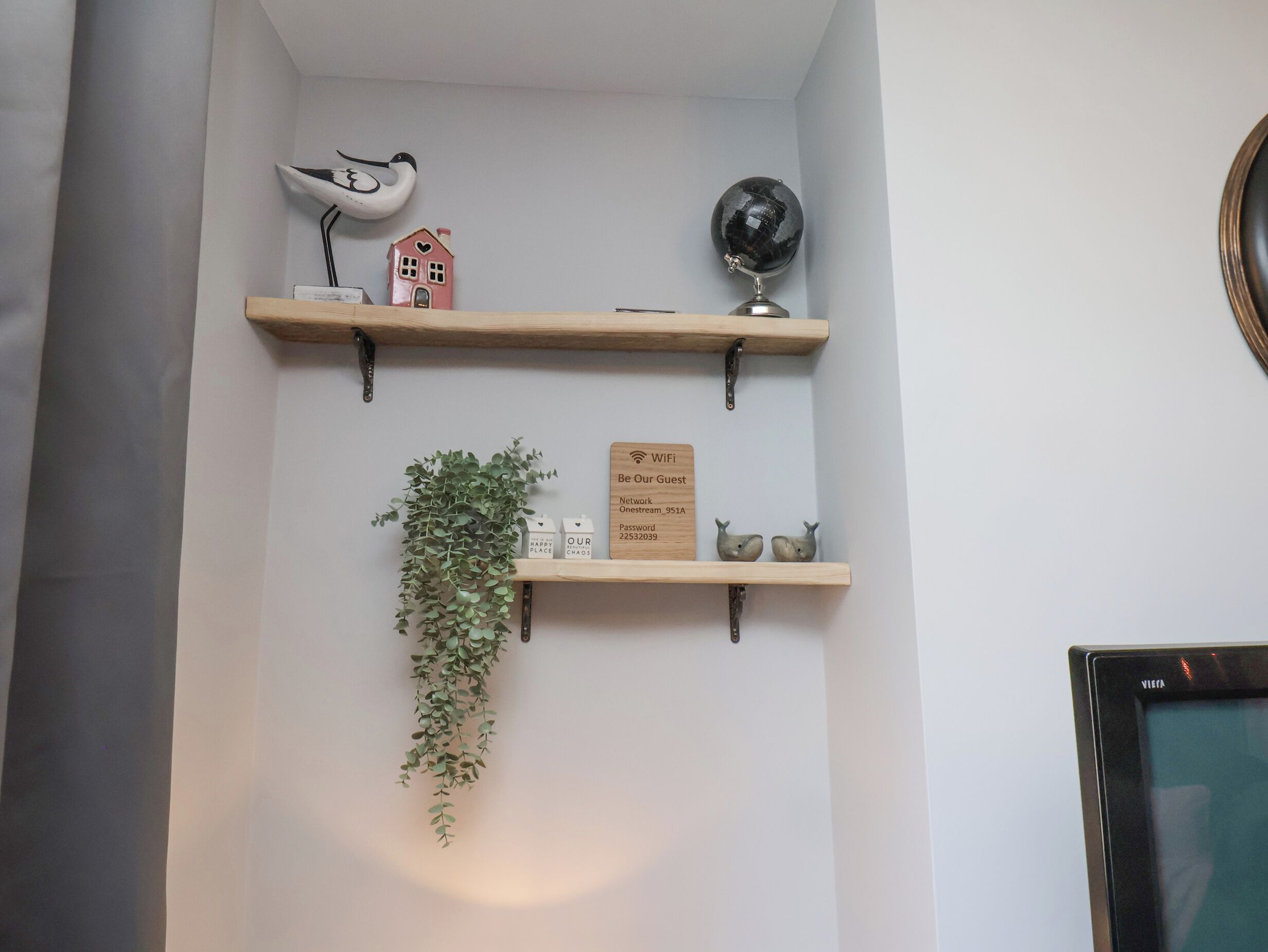 A wall with three wooden shelves, each holding various decorative items.