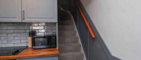 A kitchen with grey cabinets, a microwave, and a wooden countertop.