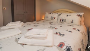 Een slaapkamer met een bed, kussens en een nachtkastje.