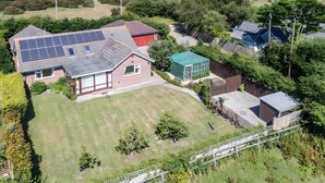 Un quartiere residenziale con una casa dotata di pannelli solari, una serra con tetto verde e un giardino recintato.
