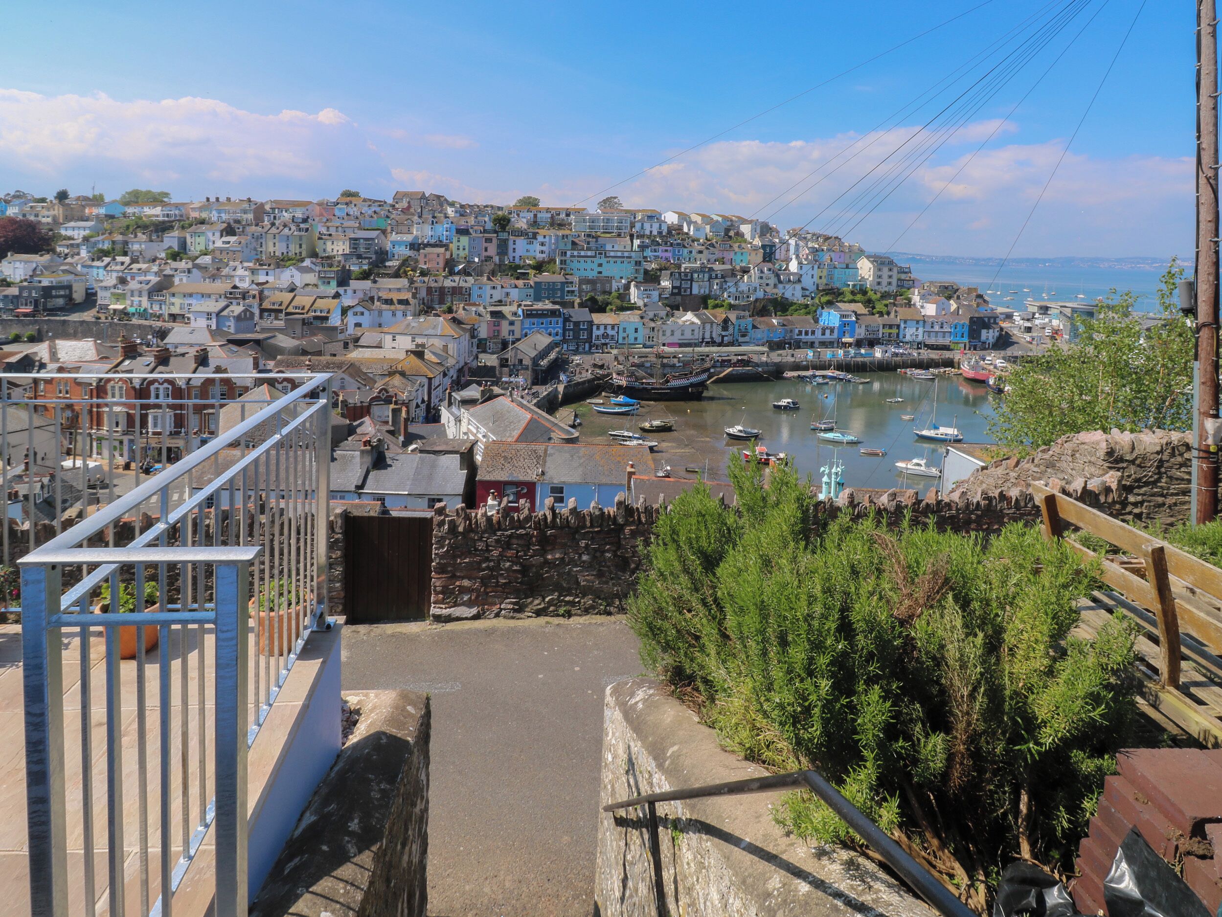 A coastal town with colorful buildings, a harbor with boats, and a stone wall.