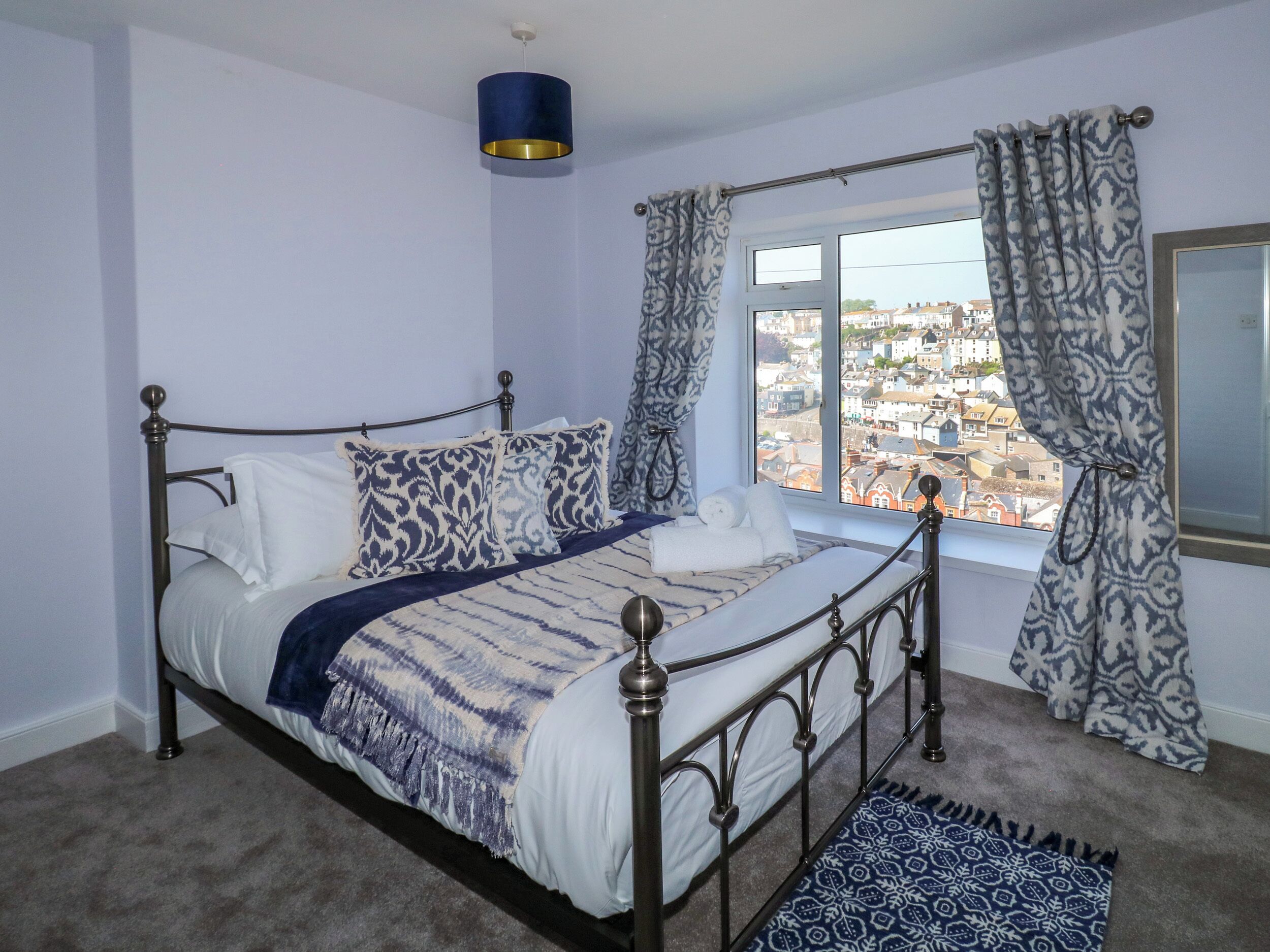 Una camera da letto con un letto, vista sulla città attraverso una finestra e un tappeto decorato.