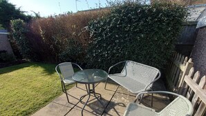 An outdoor patio with a metal table and two wicker chairs. - Sycamore (Filey)