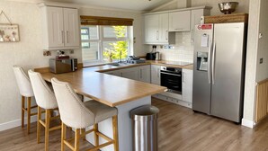 Een moderne keuken met een centraal eiland, barkrukken, een roestvrijstalen koelkast en een inbouwoven.