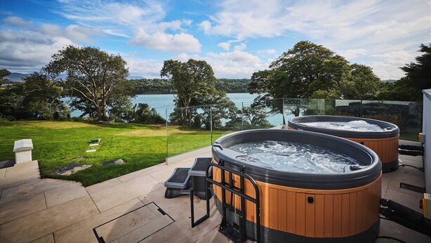 Uma  área de hidromassagem com vista para um lago e árvores.