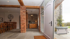 A spacious interior with a dining area, a kitchen, and a large sliding glass door leading to an outdoor patio. - Tanat House (Oswestry)