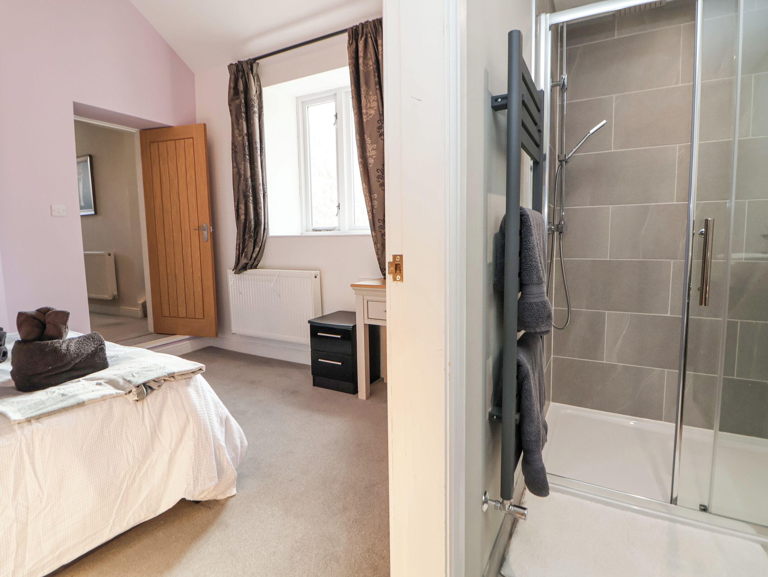 Une chambre à coucher avec un lit, une armoire en bois, un radiateur et une fenêtre avec des rideaux.