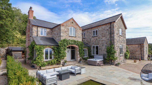 A stone house with a patio, outdoor seating, and a koi pond. - Tanat House (Oswestry)