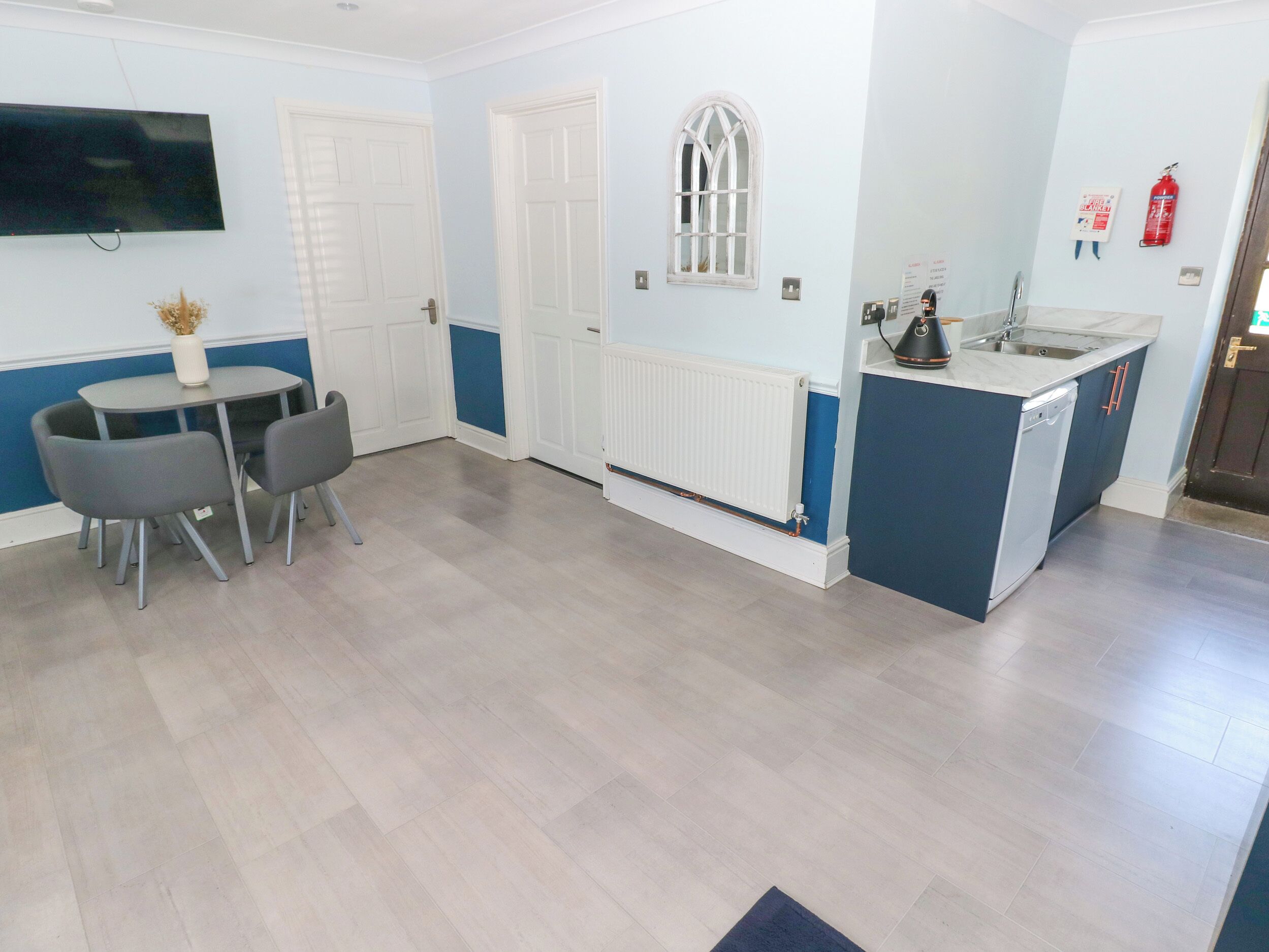 A modern kitchen with a built-in dishwasher, a small island with a sink, and a dining area with a table and chairs.