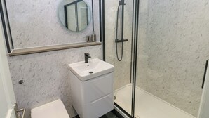 Une salle de bain moderne avec un lavabo blanc, des toilettes et une douche à parois de verre.