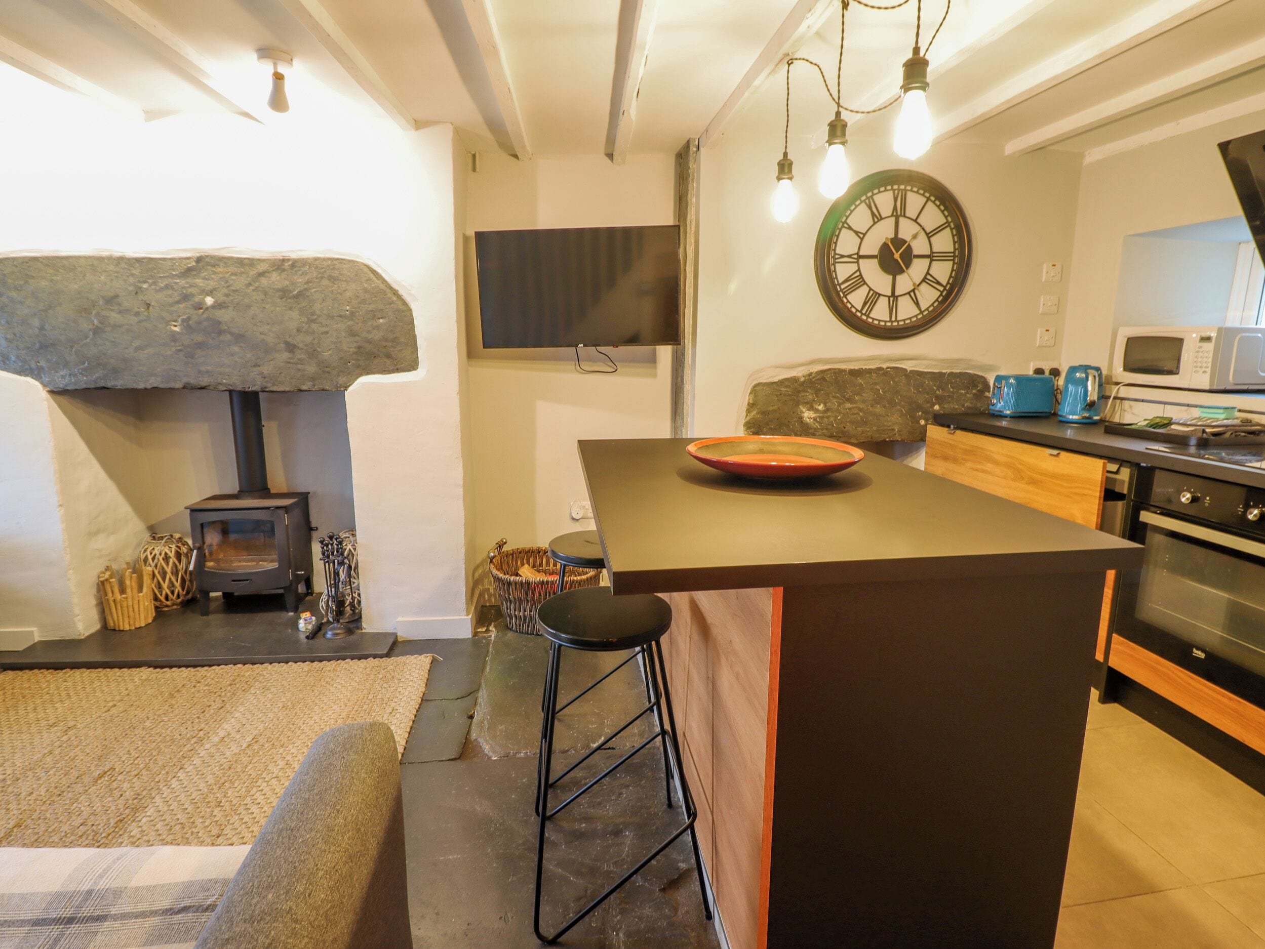Een moderne keuken met een stenen openhaard, een groot eiland, barkrukken en een magnetron.