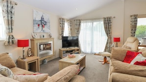 A living room with a fireplace, television, and comfortable seating. - 21 Norman Drive Lodge (Great Yarmouth)