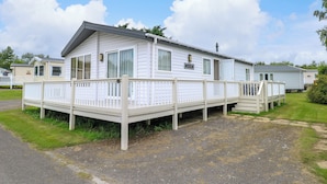 A mobile home with a covered porch and a small deck. - 21 Norman Drive Lodge (Great Yarmouth)