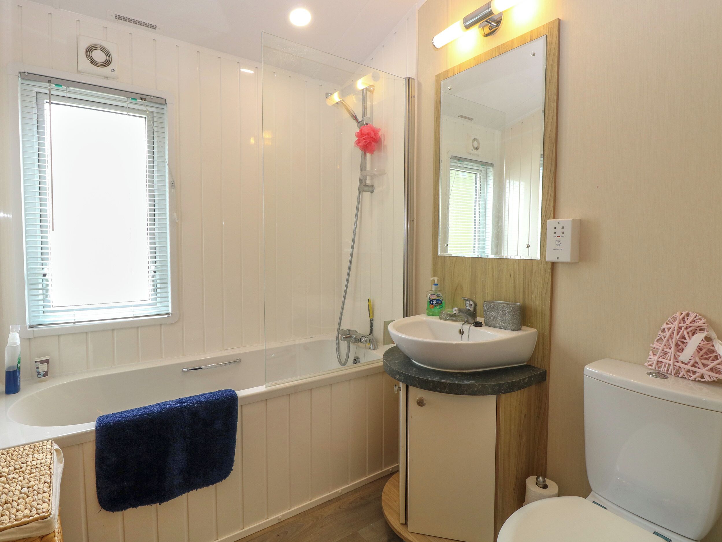A bathroom with a bathtub, a sink, a toilet, and a mirror.