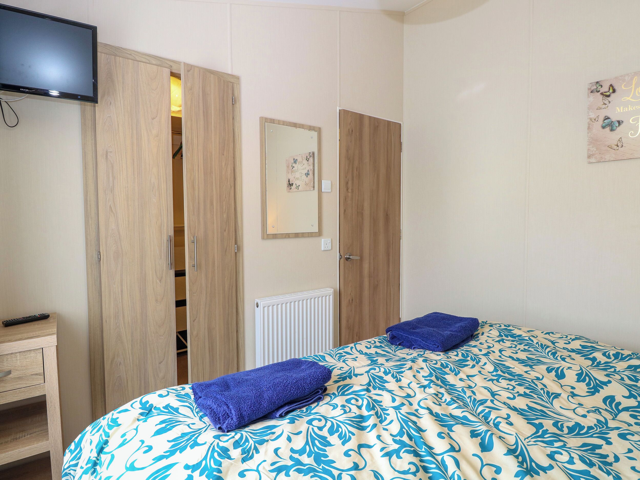 A bedroom with a bed, a TV, a wardrobe, and a radiator.
