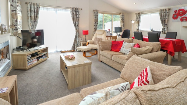 A living room with a TV, sofa, chairs, a coffee table, and a dining table. - 21 Norman Drive Lodge (Great Yarmouth)