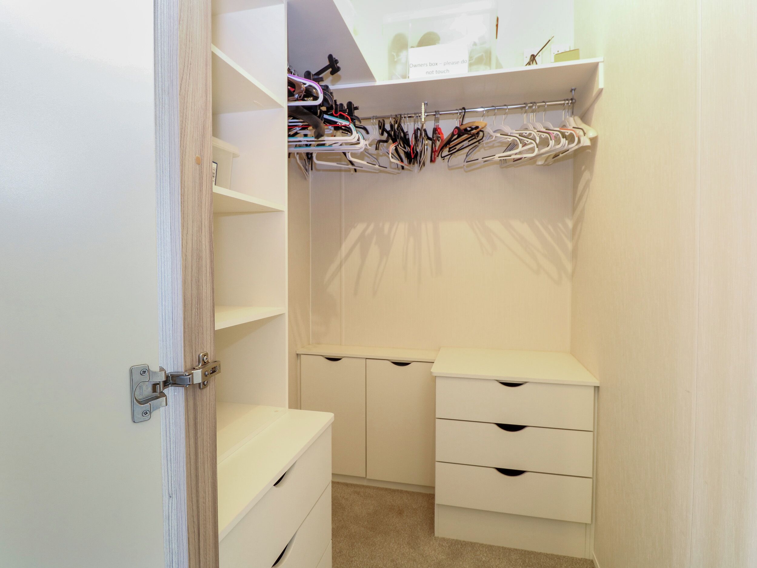 A walk-in closet with open shelves, a hanging rack, and a set of drawers.