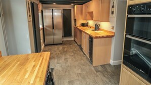A modern kitchen with a wooden countertop, stainless steel appliances, and a built-in oven. - 15 High Street (Scarborough)