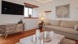 A living room with a sofa, a coffee table with candles, a TV, and a decorative wall piece. - Logan Barn (Camelford)