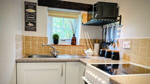 Une cuisine moderne avec des meubles blancs, un plan de travail en granit, un four encastré, un four à micro-ondes et une fenêtre donnant sur un espace verdoyant.