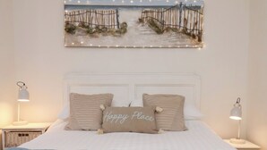 Een slaapkamer met een bed, twee bedlampen, een aan de muur hangend schilderij en een nachtkastje.