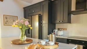 Een moderne keuken met donkere kastjes, een roestvrijstalen koelkast, een koffiezetapparaat en een vaas met bloemen op het eiland.