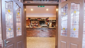 A bar entrance with a brick wall and a wooden door. - Millstone Cottages - Breidden View (Shrewsbury)