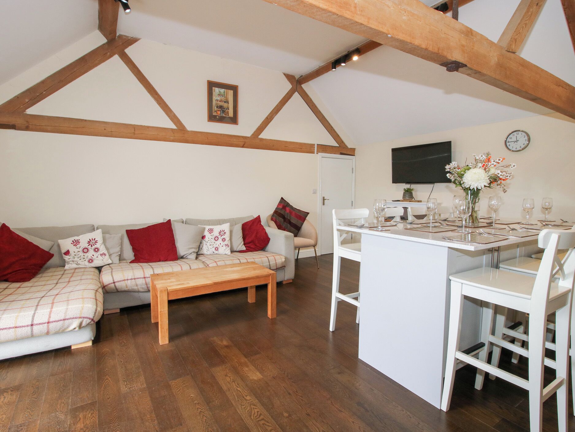 A cozy living room with a sofa, a coffee table, and a dining area set for four.