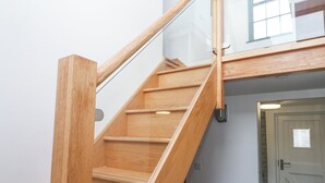 A wooden staircase with glass railings leading to an upper floor. - The Observatory Tower (Falmouth)