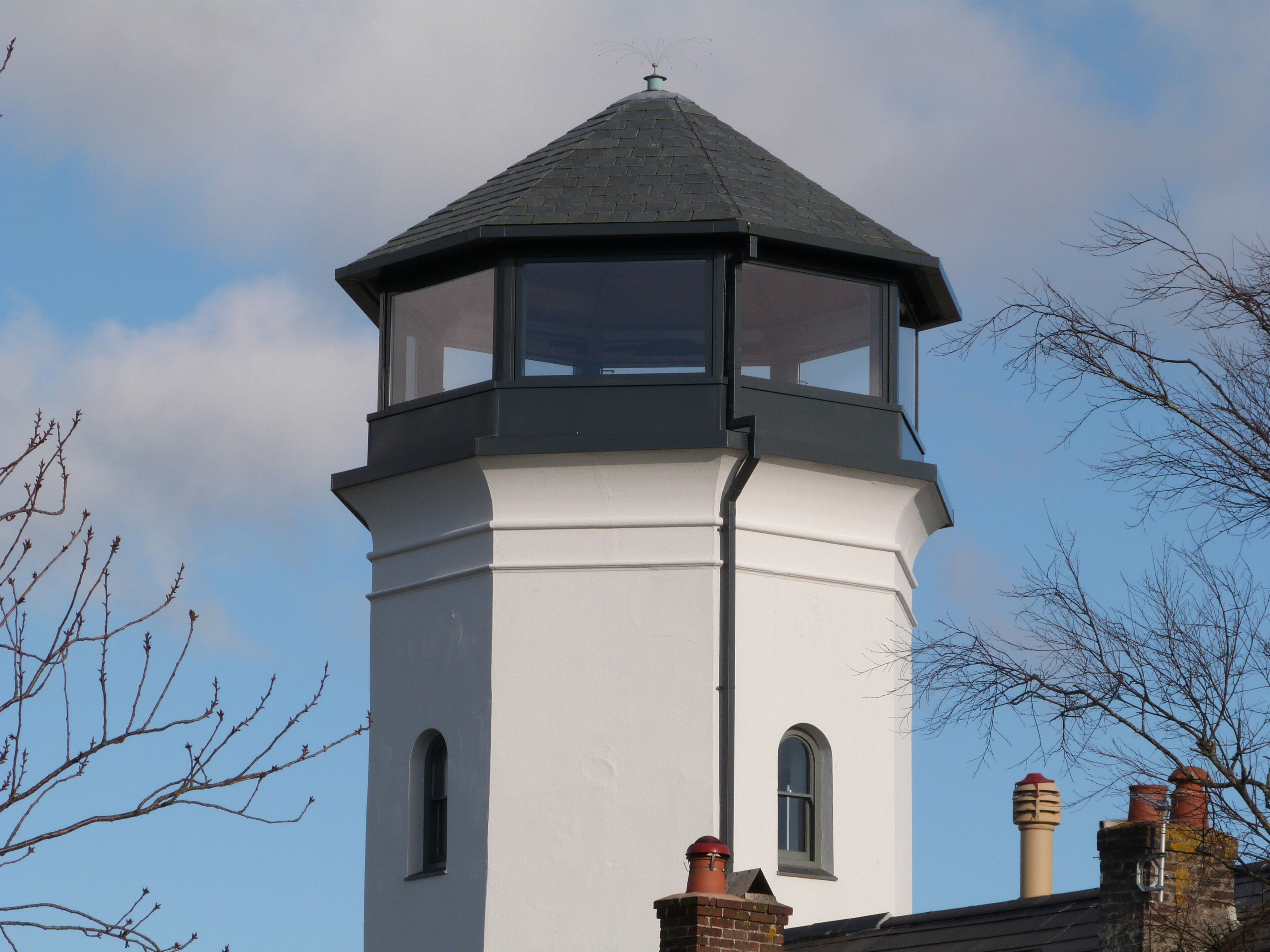 A white tower with a dark roof and a glass lantern room.