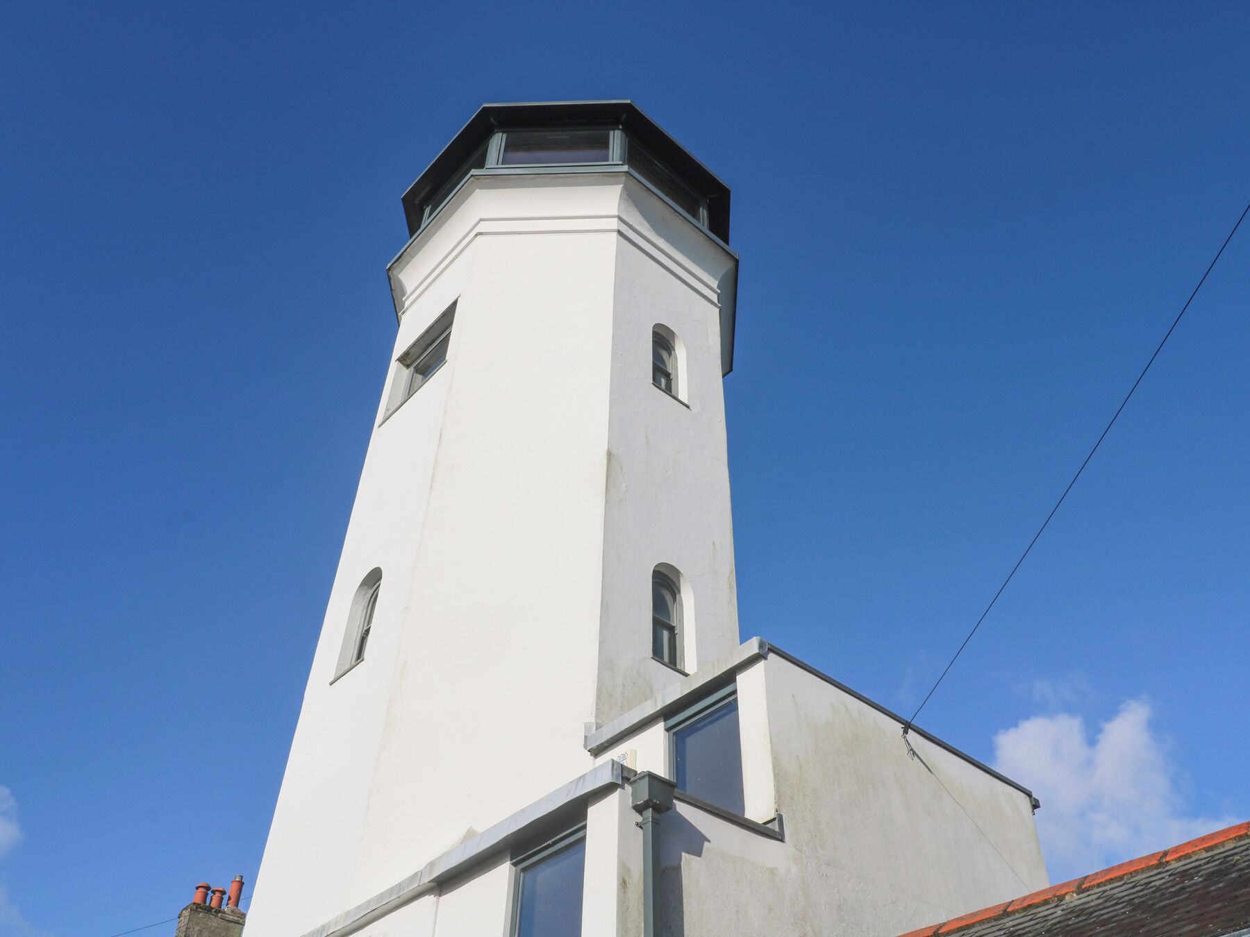 A white tower with a flat roof and a small balcony at the top.