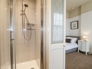 Un bagno moderno con doccia vetro, vasca da bagno bianca e soffione separato.