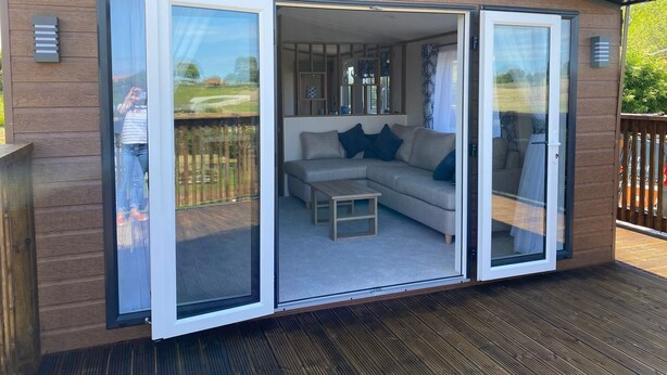 A modern outdoor living space with a sliding glass door, a cushioned sofa, and a coffee table.