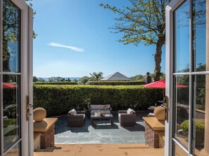 Een terras met tuinmeubilair en uitzicht op de oceaan.