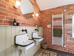 A bathroom with two white sinks, a mirror, and a brick wall. - Hazel Cottage - Fold Yards (Matlock)