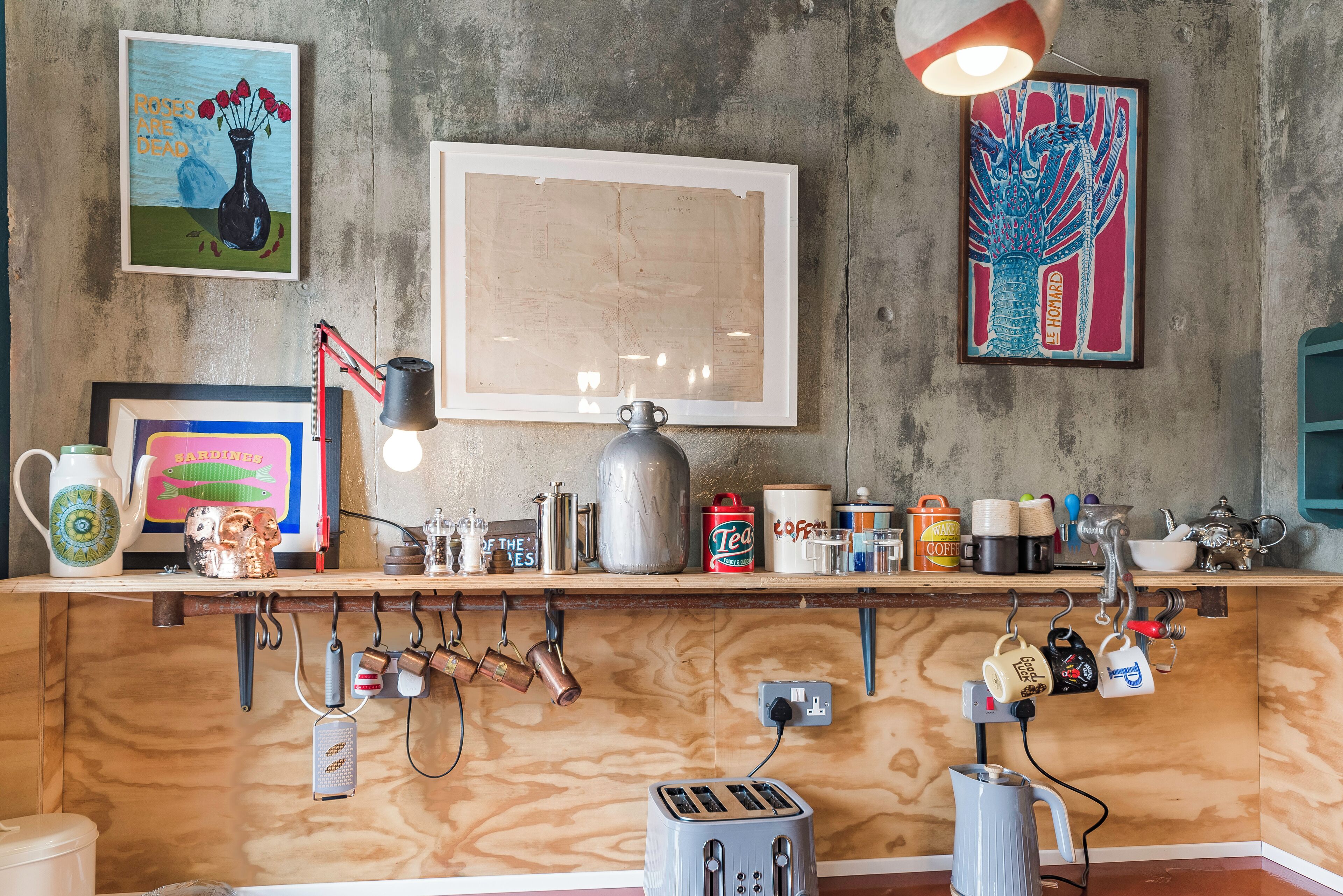 A kitchen with wooden cabinets, a coffee machine, a kettle, and various mugs and containers on the counter.