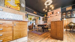 A room with wooden floors, a dining area with chairs and a table, a wooden cabinet, and a clock on the wall. - Pats Palace (Whitley Bay)